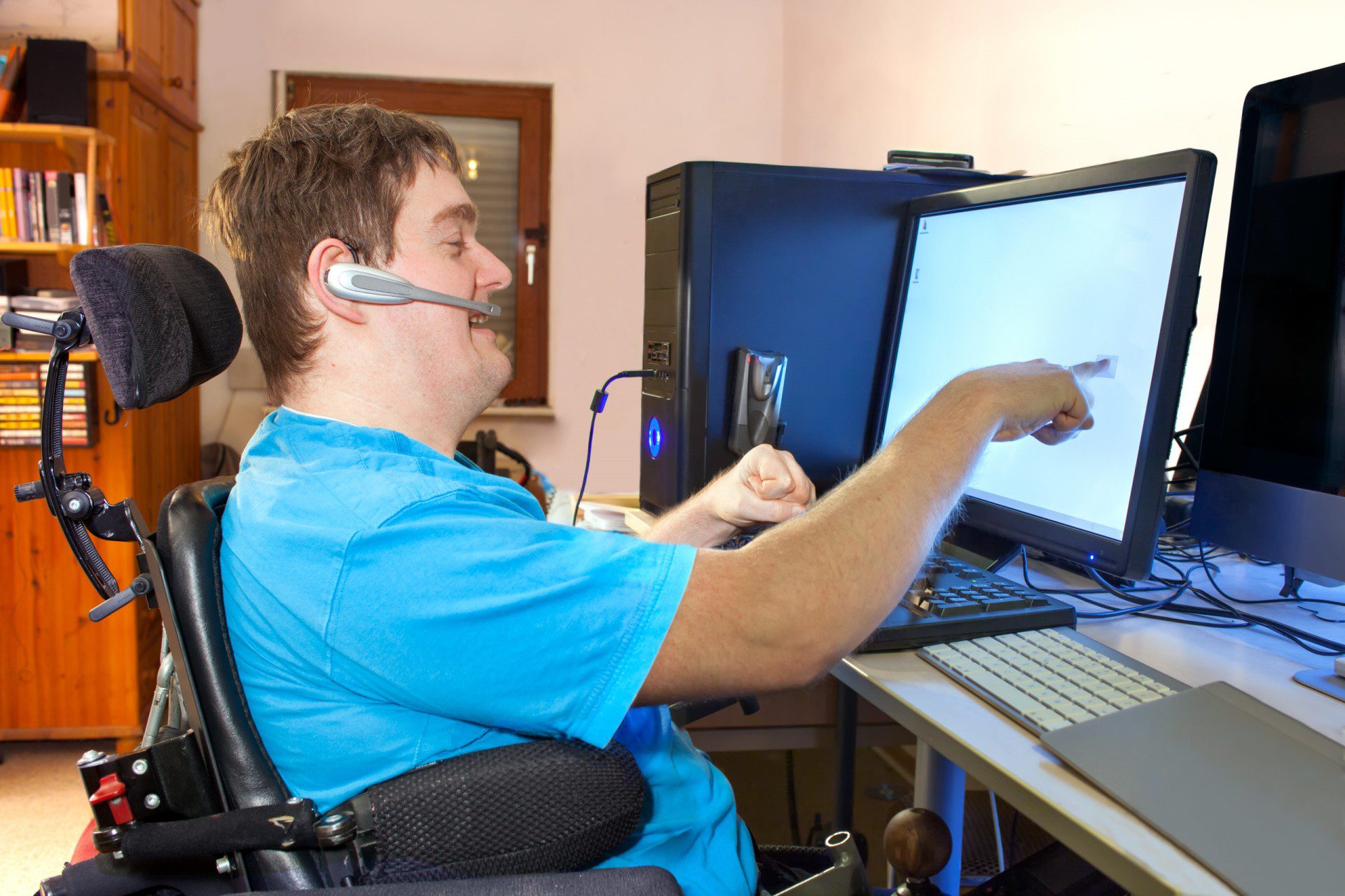man using a touch screen and microphone headset for information and communication technology accessibility